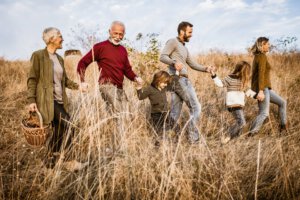 Glückliche Großfamilie auf der Suche nach dem richtigen Picknickplatz auf dem Feld.