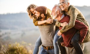 Sorgloser älterer Vater und erwachsener Sohn huckepack ihre Frauen im Herbst.